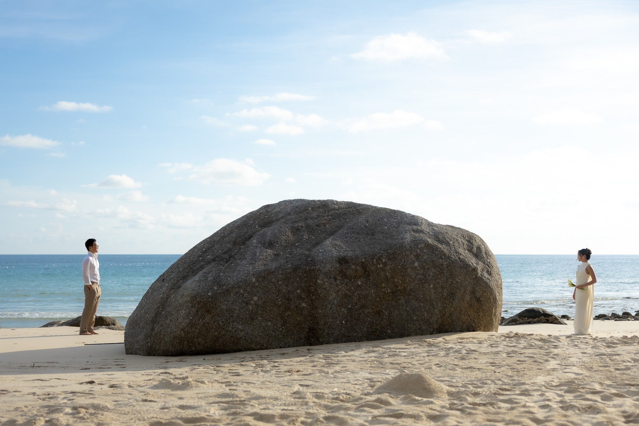 The couple by a boulder on the shore